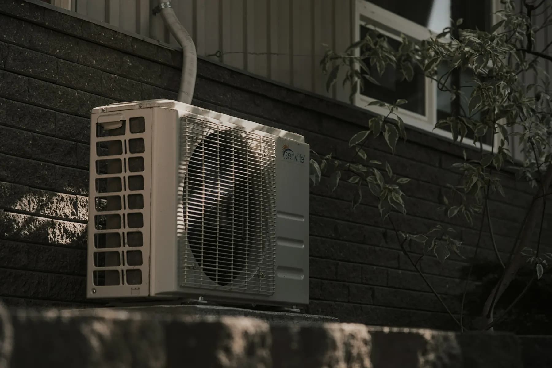 Unité extérieure de climatisation au pied d'une façade sombre
