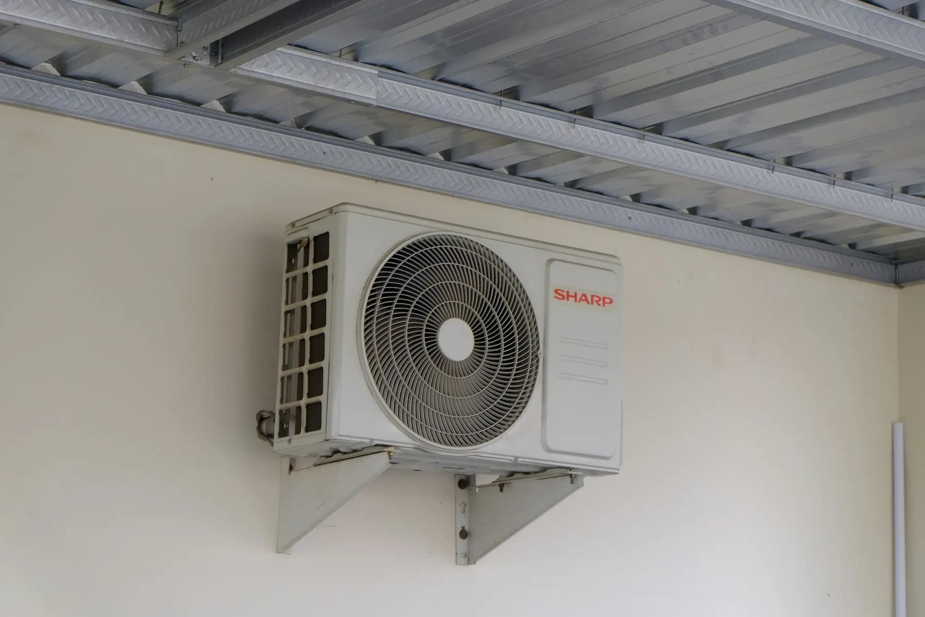 Unité extérieure de climatisation fixée au mur sur équerres