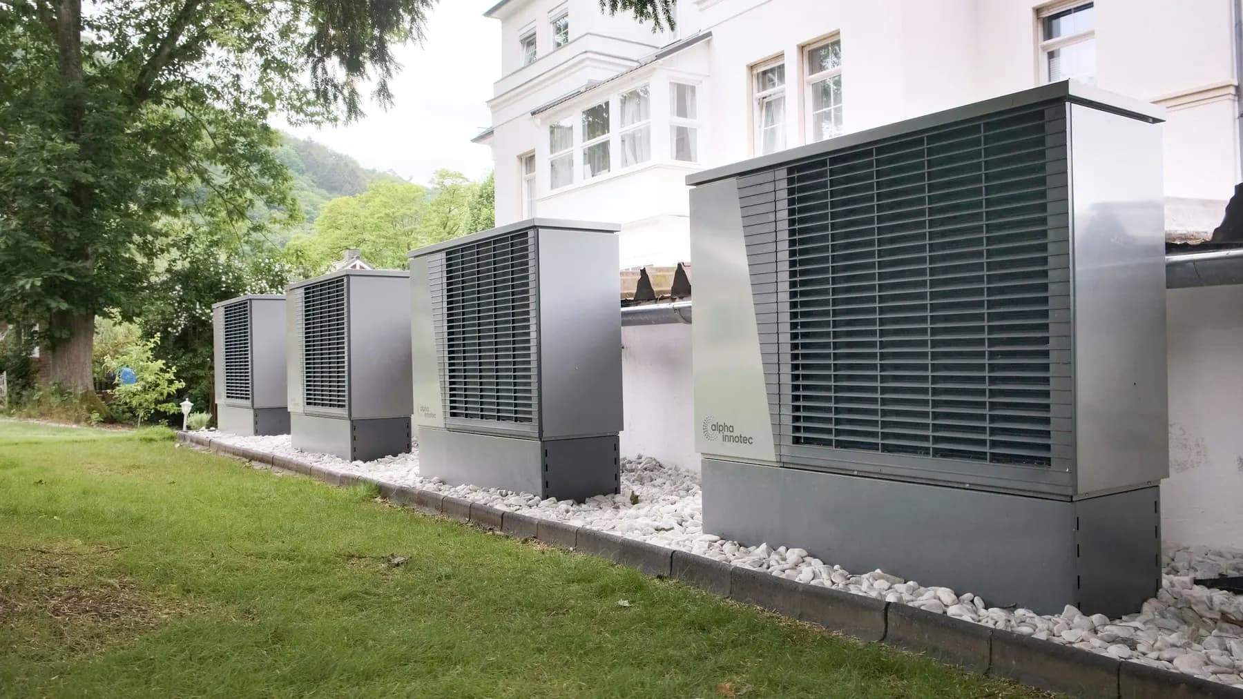 Quatre pompes à chaleur alignées devant un immeuble